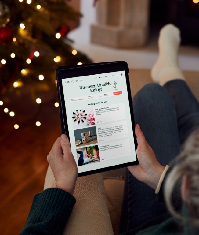 Woman At Home Using Digital Tablet To Shop For Clothes Online At Christmas